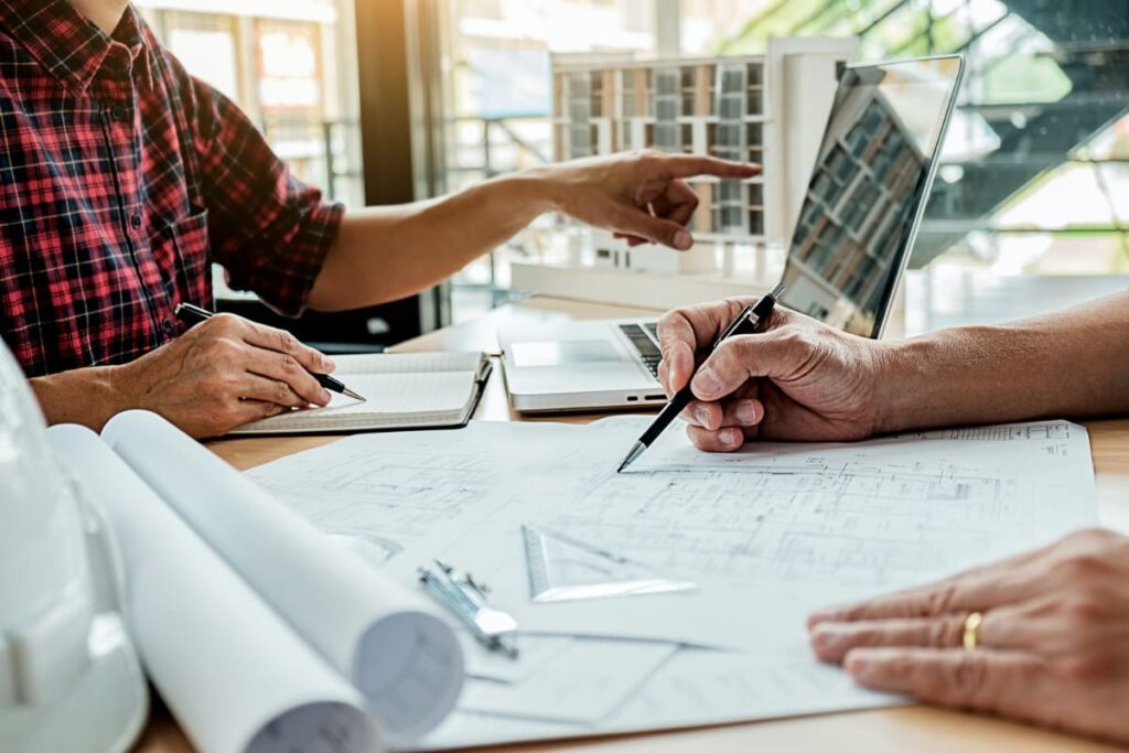 barbati care se uita pe planurile de constructie a unei case